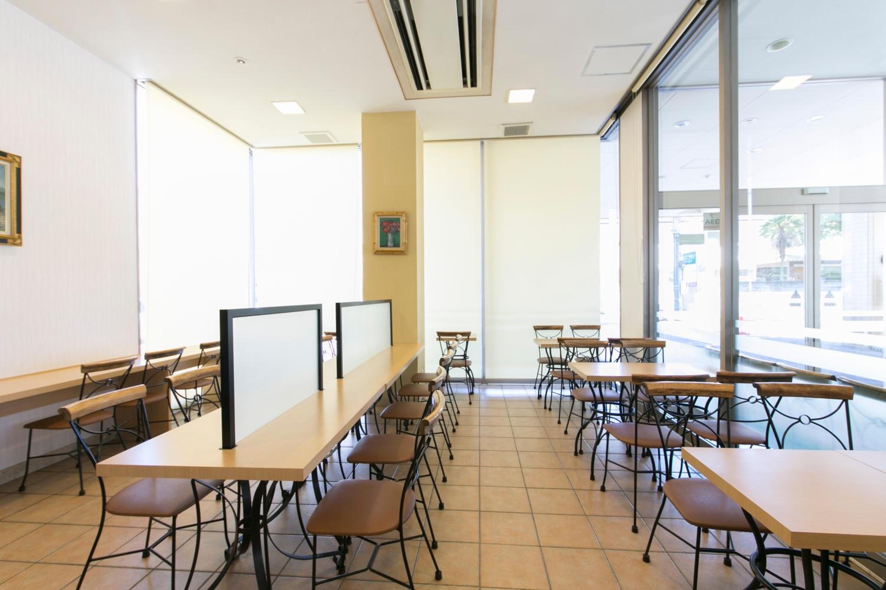 A classroom with multiple tables and chairs, large windows, and a whiteboard.