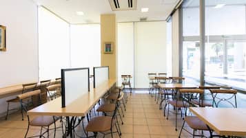 A classroom with multiple tables and chairs, large windows, and a whiteboard.