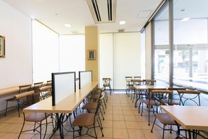 A classroom with multiple tables and chairs, large windows, and a whiteboard. - Hotel Econo Yokkaichi (Yokkaichi)