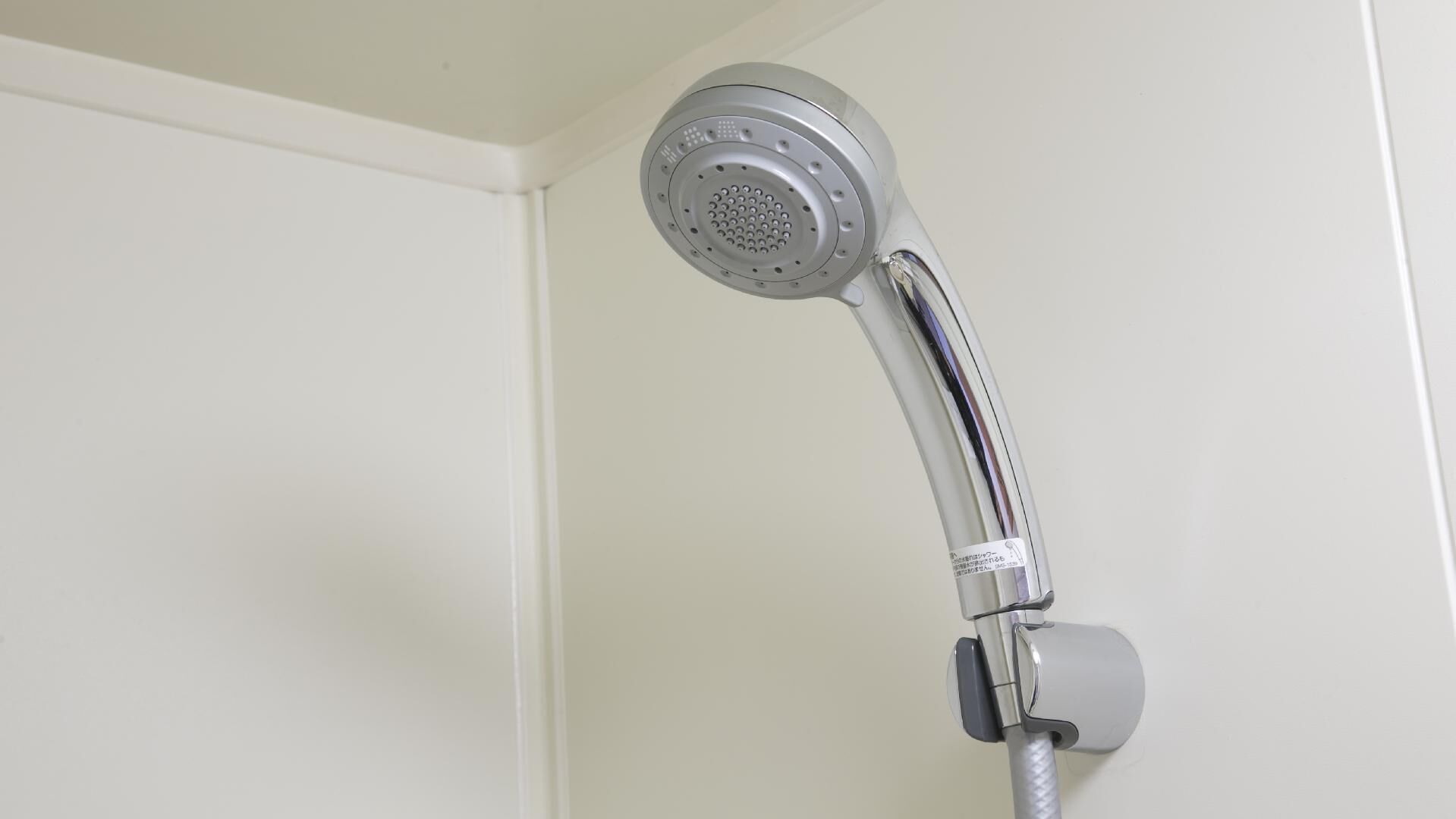 Un pommeau de douche fixé au mur, avec une molette de réglage.
