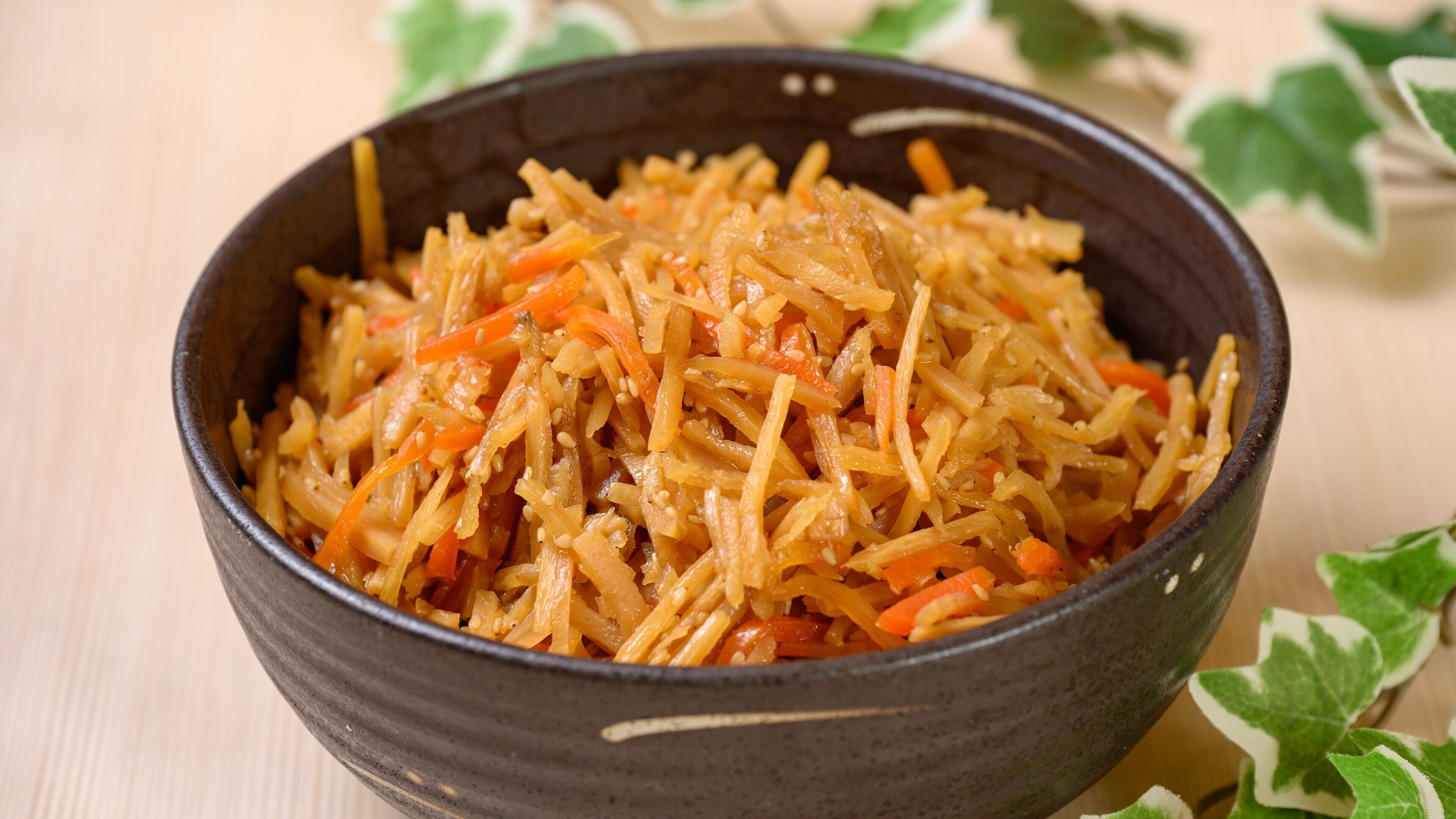 A bowl of shredded vegetables, possibly carrots and cabbage, with sesame seeds sprinkled on top.