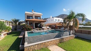 A modern two-story house with a swimming pool, stone walls, and a mountain backdrop. - Villa Del Nonno (Rhodes)