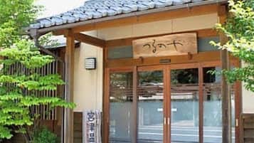 A traditional Japanese building with a tiled roof, wooden entrance, and signage.