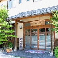 Edificio japonés tradicional con tejado de tejas, entrada de madera y señalización.