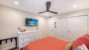 A bedroom with a bed, dresser, ceiling fan, and a painting of a beach scene. - House Of The Sun #302GS (Sarasota)