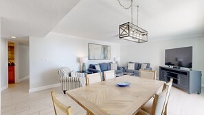A modern living room with a dining table, sofas, and a television.