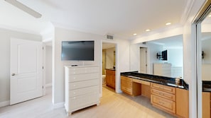 A modern bathroom with a vanity, mirror, and a television mounted above the mirror.