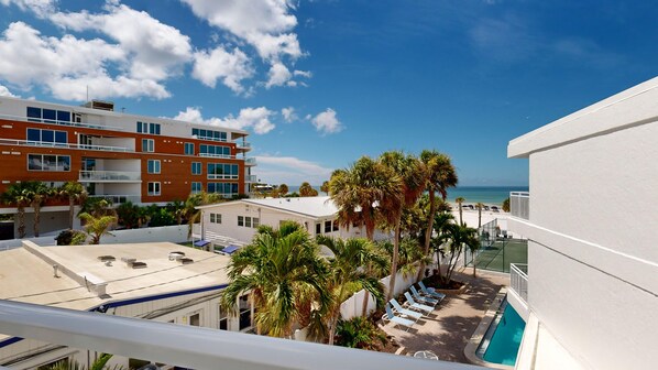 A hotel with a pool, palm trees, and a view of the ocean.