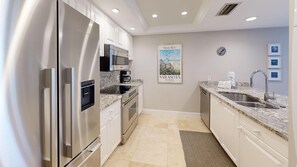 A modern kitchen with stainless steel appliances, a granite countertop, and a poster of Sarasota, Florida.