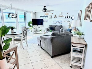 A modern living room with a grey sofa, a television, and a ceiling fan.