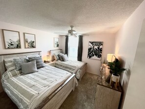 Ein Schlafzimmer mit zwei Betten, einem Deckenventilator und Bildern an den Wänden.