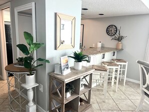 A modern kitchen with white cabinetry, a wooden island, and bar stools.