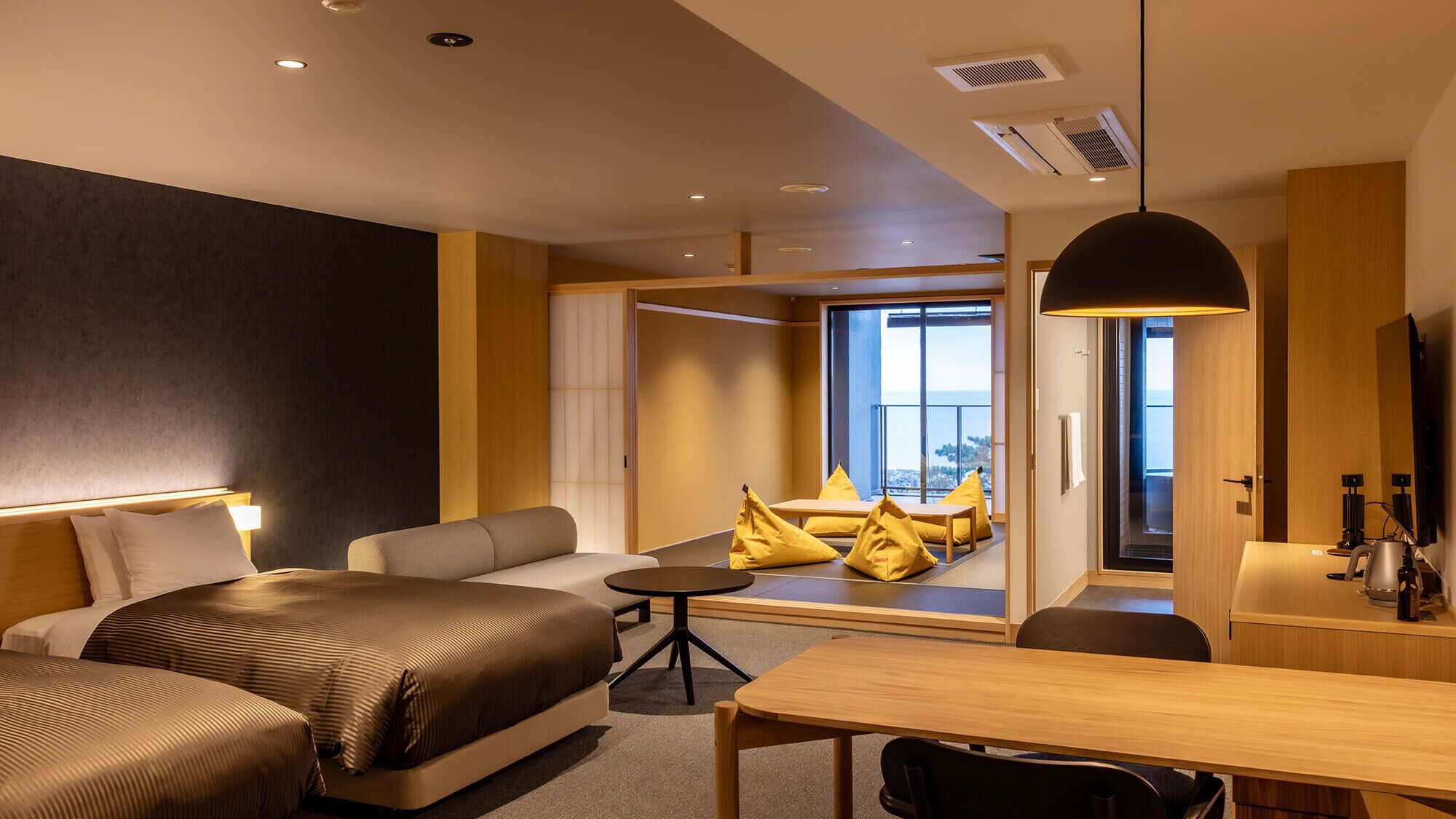 Une chambre d’hôtel moderne équipée d’un lit, d’un canapé, d’une table à manger et offrant une vue sur l’extérieur.