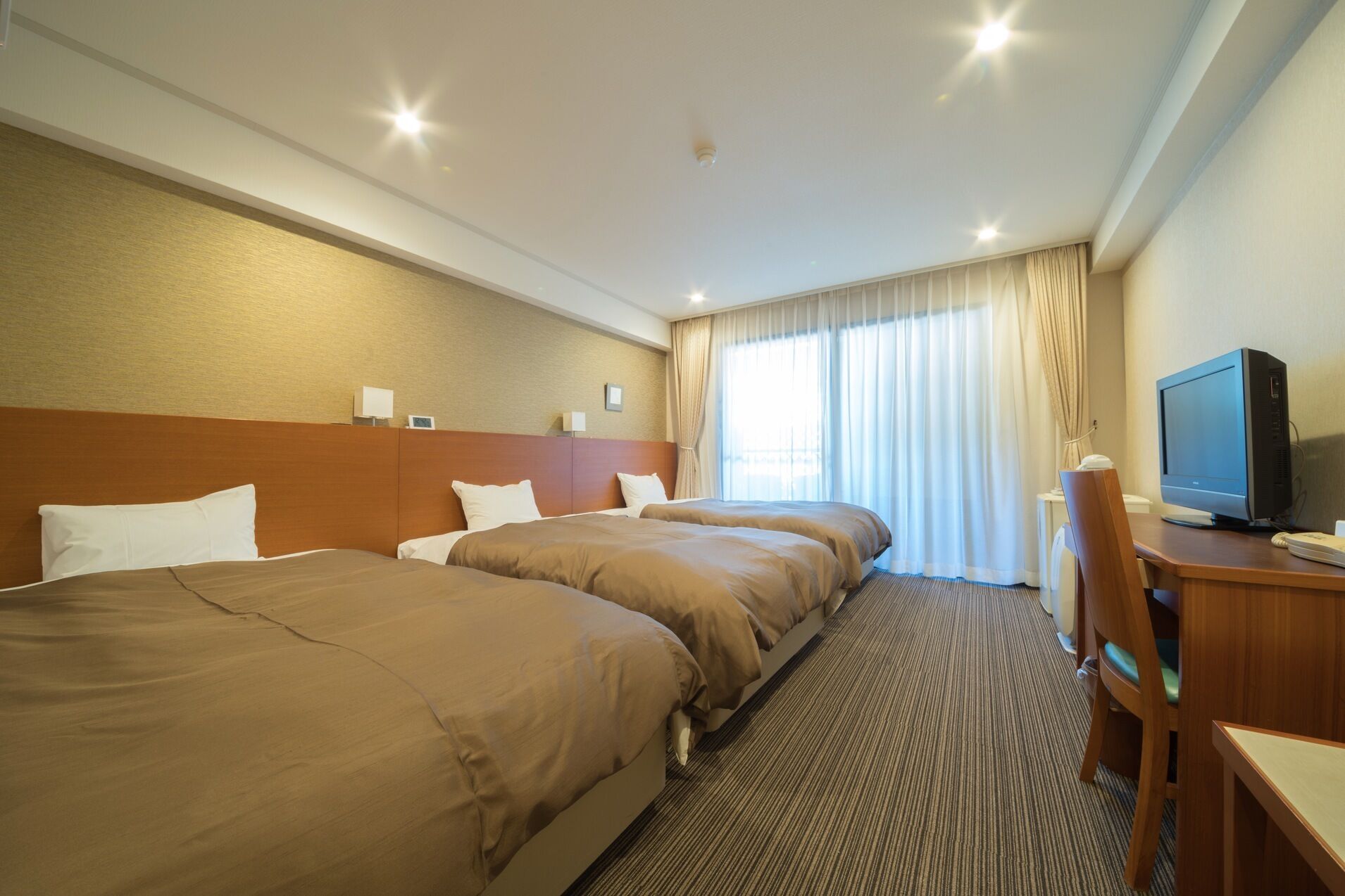 Une chambre d’hôtel avec deux lits, un bureau avec un ordinateur et une télévision.