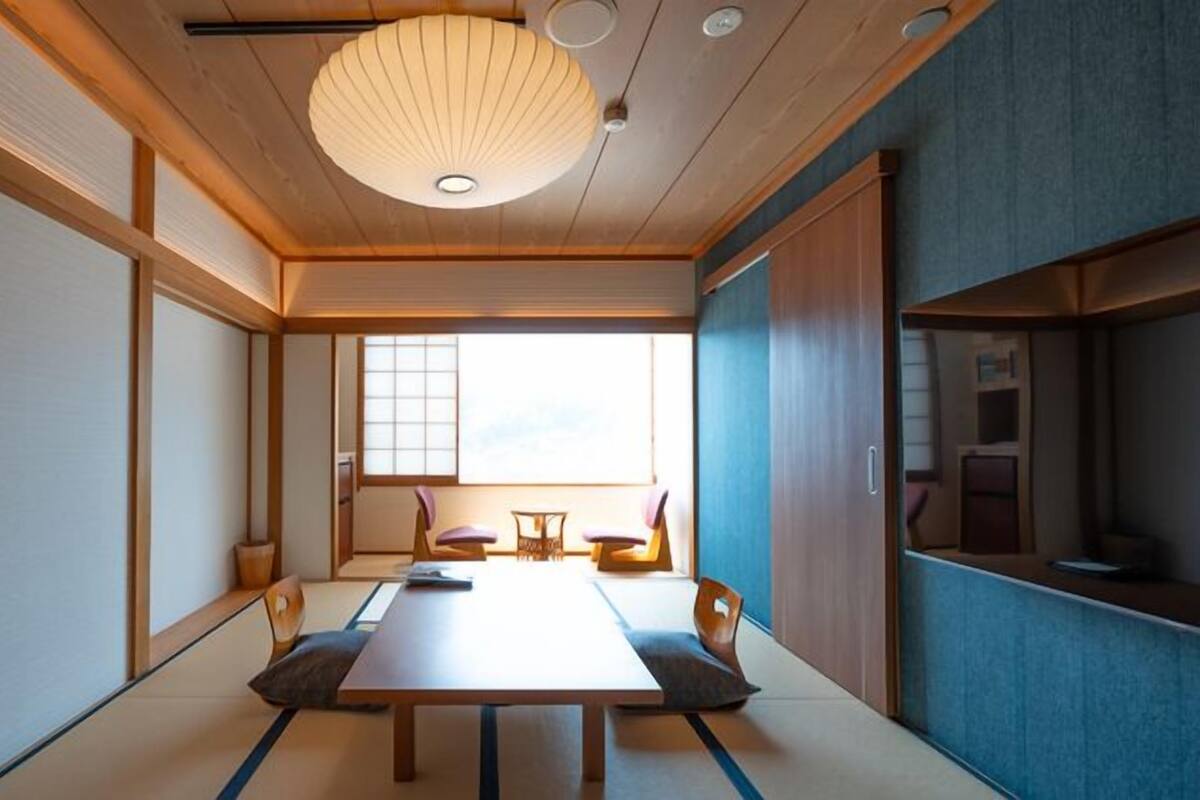 Um quarto japonês tradicional com tatames, uma mesa baixa e portas deslizantes.