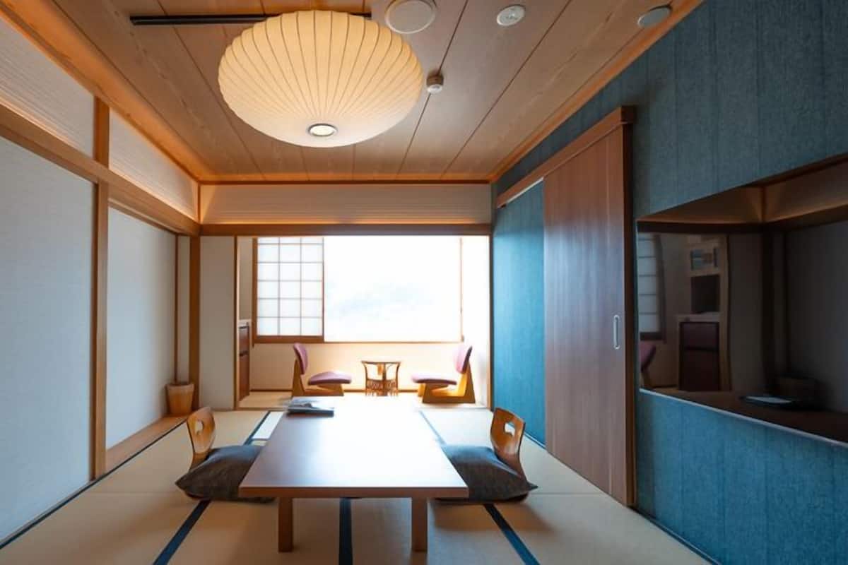 Una habitación japonesa tradicional con suelo de tatami, una mesa baja y puertas correderas.
