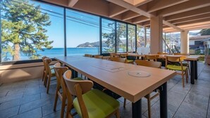 A spacious outdoor dining area with large windows overlooking a coastal view. - Atami Onsen New Tomiyoshi (Atami)