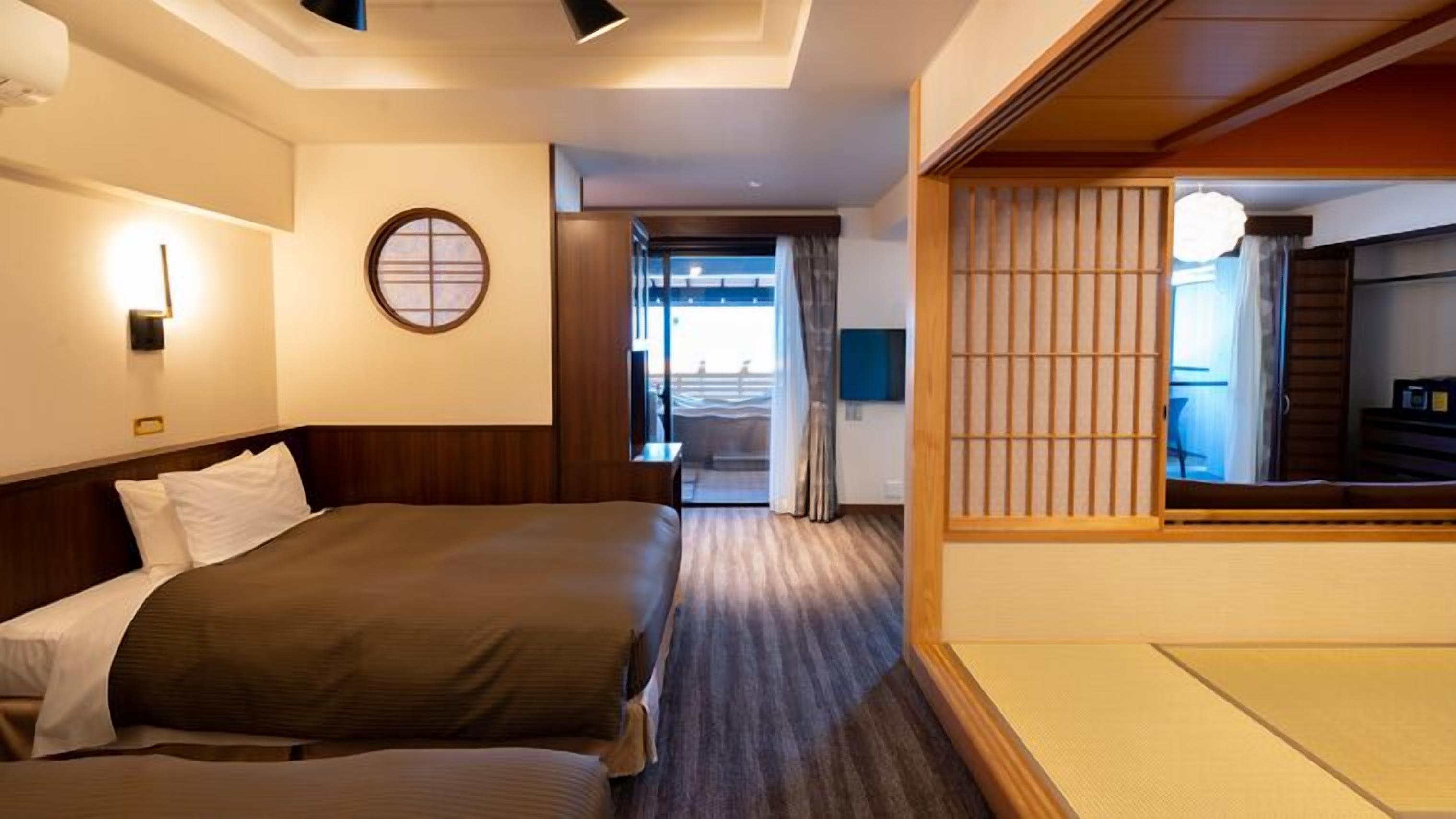 A hotel room with two beds, a view of the balcony, and a traditional Japanese shoji screen.