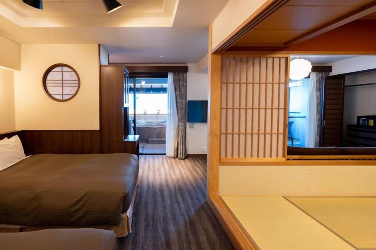 A hotel room with two beds, a view of the balcony, and a traditional Japanese shoji screen.