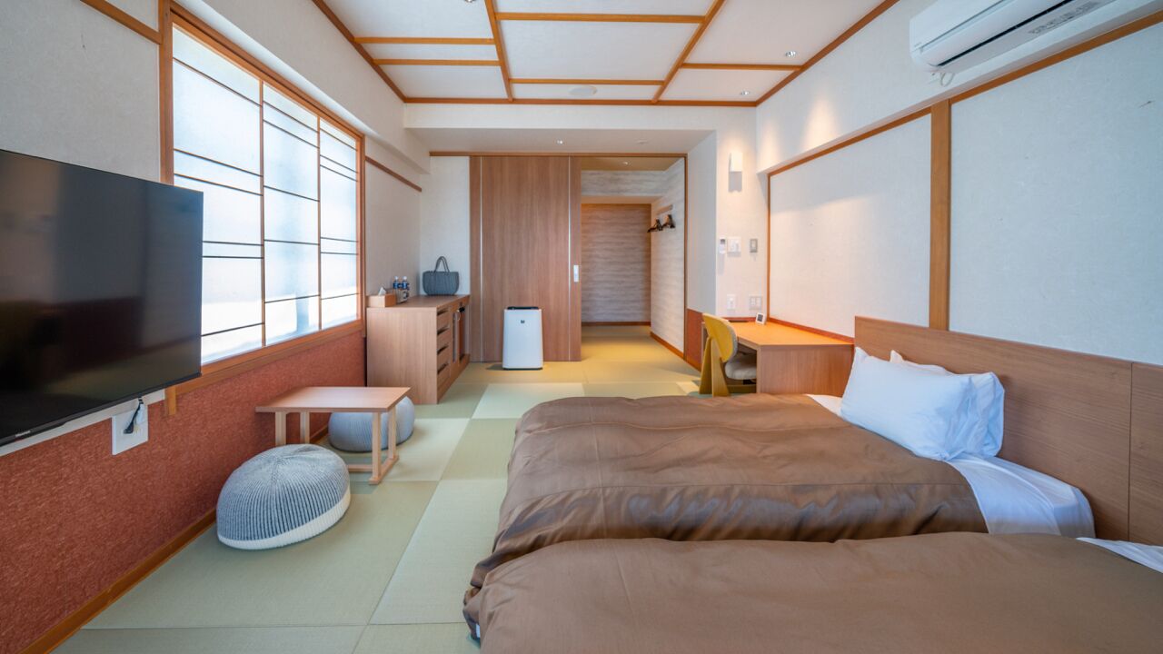 Une chambre d’hôtel équipée d’un lit, d’une télévision, d’un bureau, d’une chaise, d’une petite table et d’un réfrigérateur.