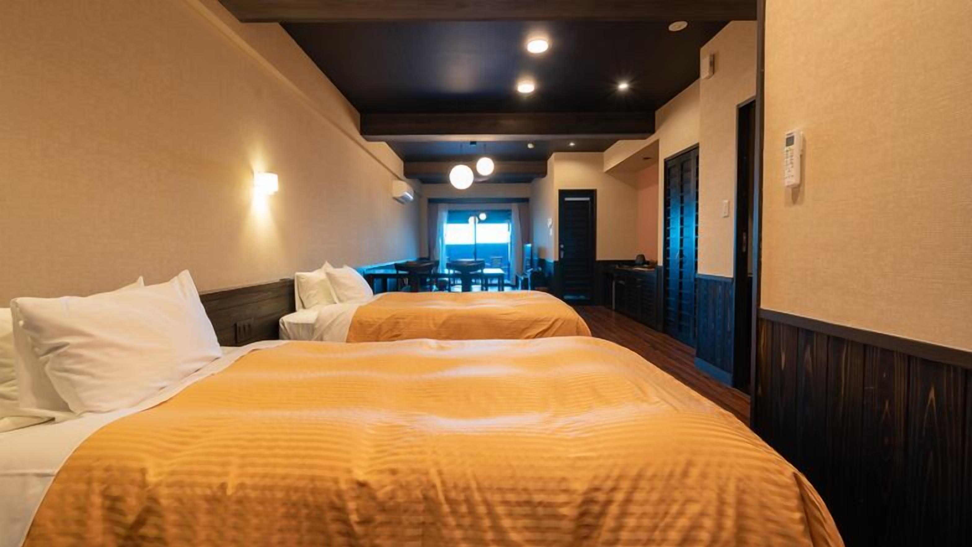 Une chambre d’hôtel avec deux lits, un bureau et vue sur la mer.