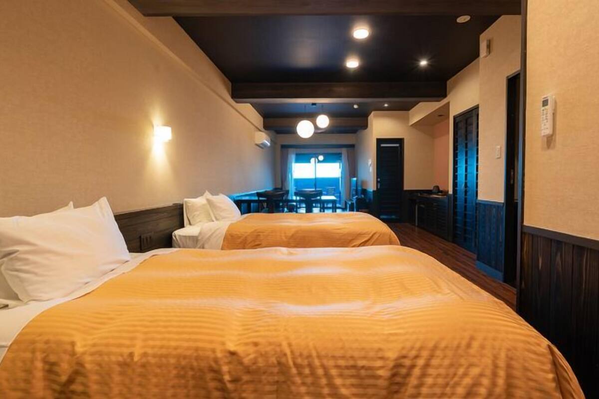 Quarto de hotel com duas camas, uma escrivaninha e vista para o mar.
