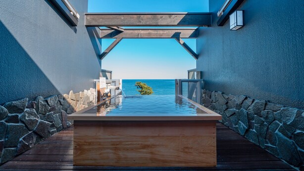 A wooden infinity pool with a stone border, leading to a clear view of the ocean. - Atami Onsen New Tomiyoshi (Atami)