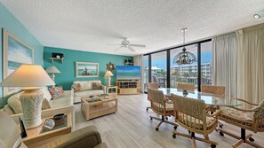 Ein geräumiges Wohnzimmer mit großem Fernseher, bequemen Sitzmöglichkeiten und einem Balkon mit Blick.