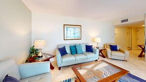 Uma sala de estar moderna com um sofá azul claro, uma mesa de centro de madeira e duas mesas laterais com luminárias.