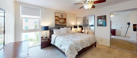 A bedroom with a bed, nightstands, a ceiling fan, and a large mirror.