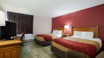 Habitación de hotel con dos camas, un escritorio con televisor y una ventana con cortinas.