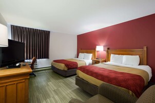 Habitación de hotel con dos camas, un escritorio con televisor y una ventana con cortinas.