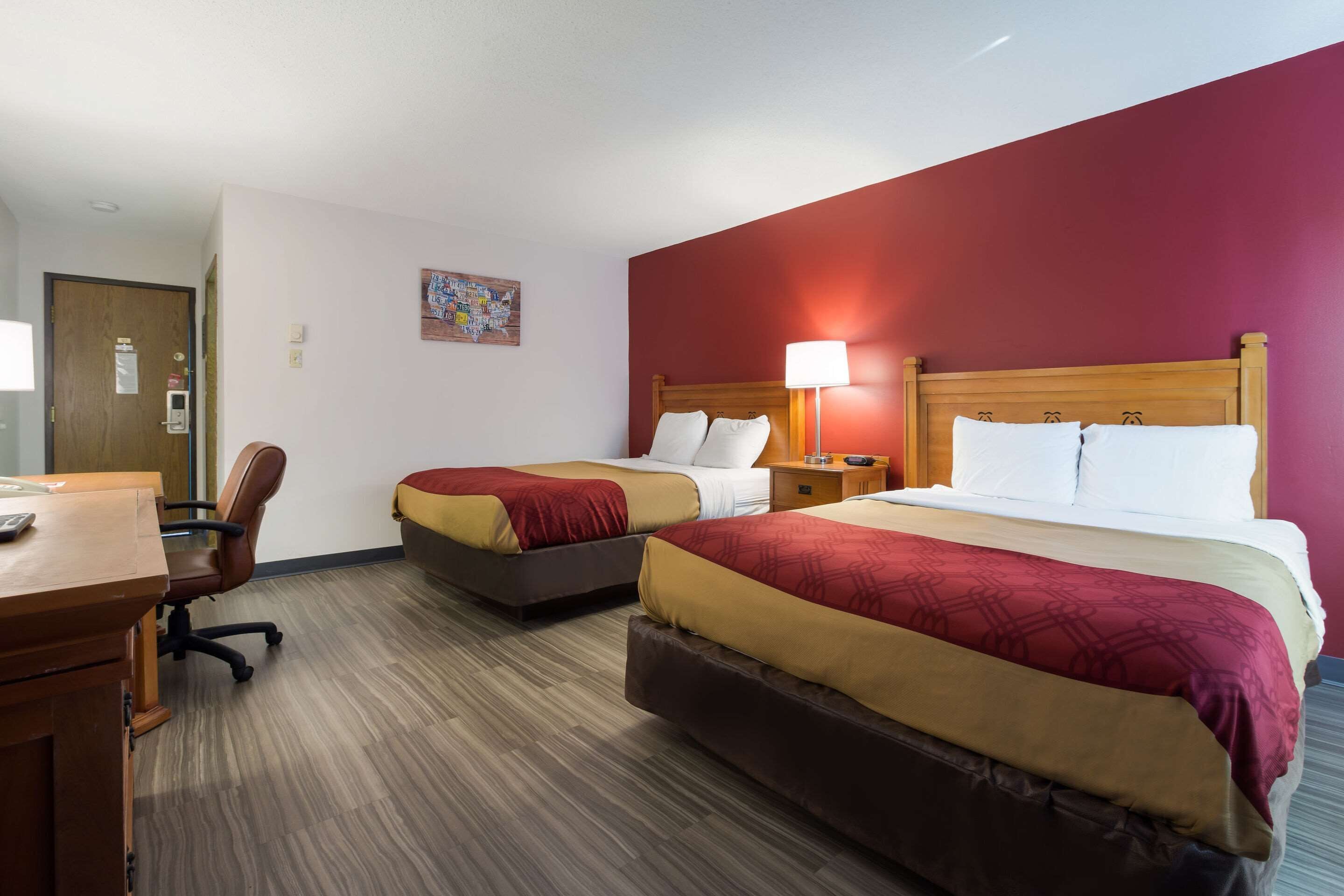 A hotel room with two beds, a desk, and a chair.