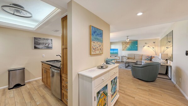 A modern living space with a kitchen, dining area, and a seating area with a sofa and a coffee table. - House Of The Sun #216GF (Sarasota)