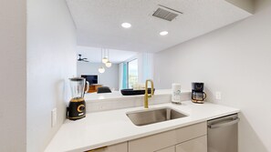 A modern kitchen with a stainless steel sink, a coffee maker, and a blender.