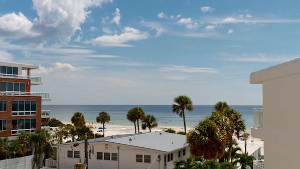 A beachfront property with a view of the ocean, palm trees, and adjacent buildings. - Gulf View Condo with On-site Management - 411 (Sarasota)