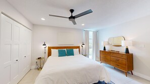 A bedroom with a bed, a dresser, a ceiling fan, and a window with curtains. - Gulf View Condo with On-site Management - 411 (Sarasota)