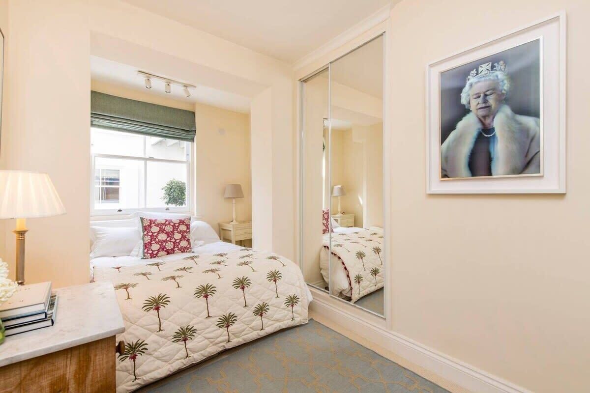 Une chambre d’hôtel avec un lit, une table de chevet avec une lampe, un miroir et un tableau encadré au mur.