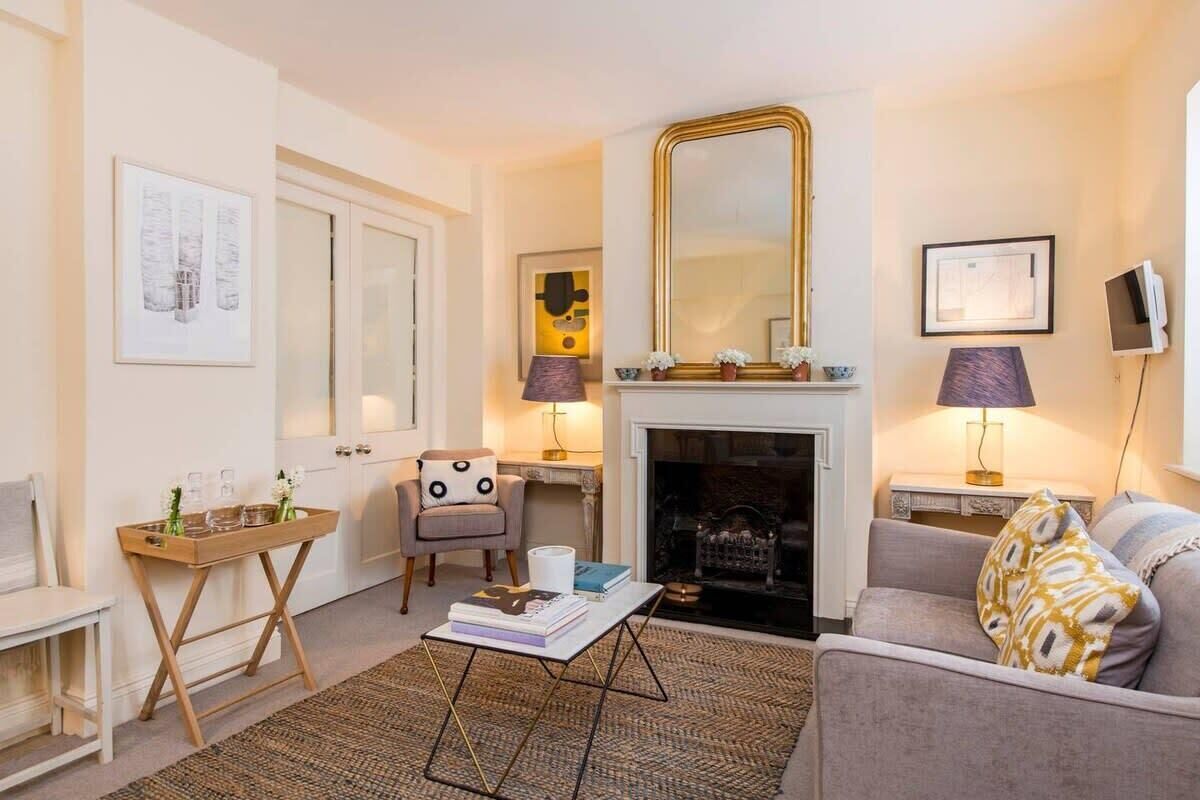 A living room with a fireplace, a sofa, a coffee table, a chair, and a TV.