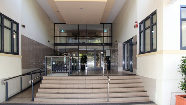 A modern building entrance with a double staircase, glass railings, and a potted plant. - ADELAIDE CBD APARTMENT - 3BR, 2BATH & CARPARK (Adelaide)