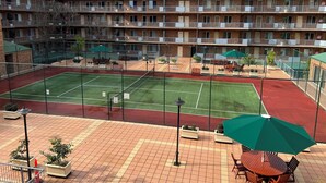 A multi-story hotel with a tennis court, outdoor seating, and a fenced patio area. - ADELAIDE CBD APARTMENT - 3BR, 2BATH & CARPARK (Adelaide)