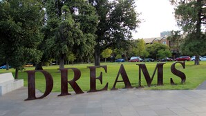 A large metal sign with the word "DREAMS" in the foreground, set in a park with grass and trees in the background. - ADELAIDE CBD APARTMENT - 3BR, 2BATH & CARPARK (Adelaide)