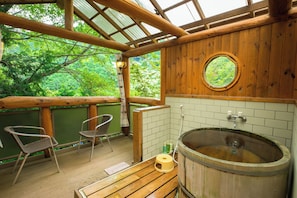 Une cabane en bois avec une baignoire en bois, deux chaises et une table en bois.