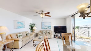 A modern living room with a sofa, coffee table, TV, and a balcony with a view. - Gulf-Side Siesta Key Getaway with Beautiful Beach Views (Sarasota)