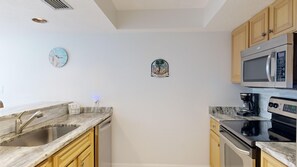 A kitchen with a sink, a microwave, a stove, and wooden cabinets. - Gulf-Side Siesta Key Getaway with Beautiful Beach Views (Sarasota)