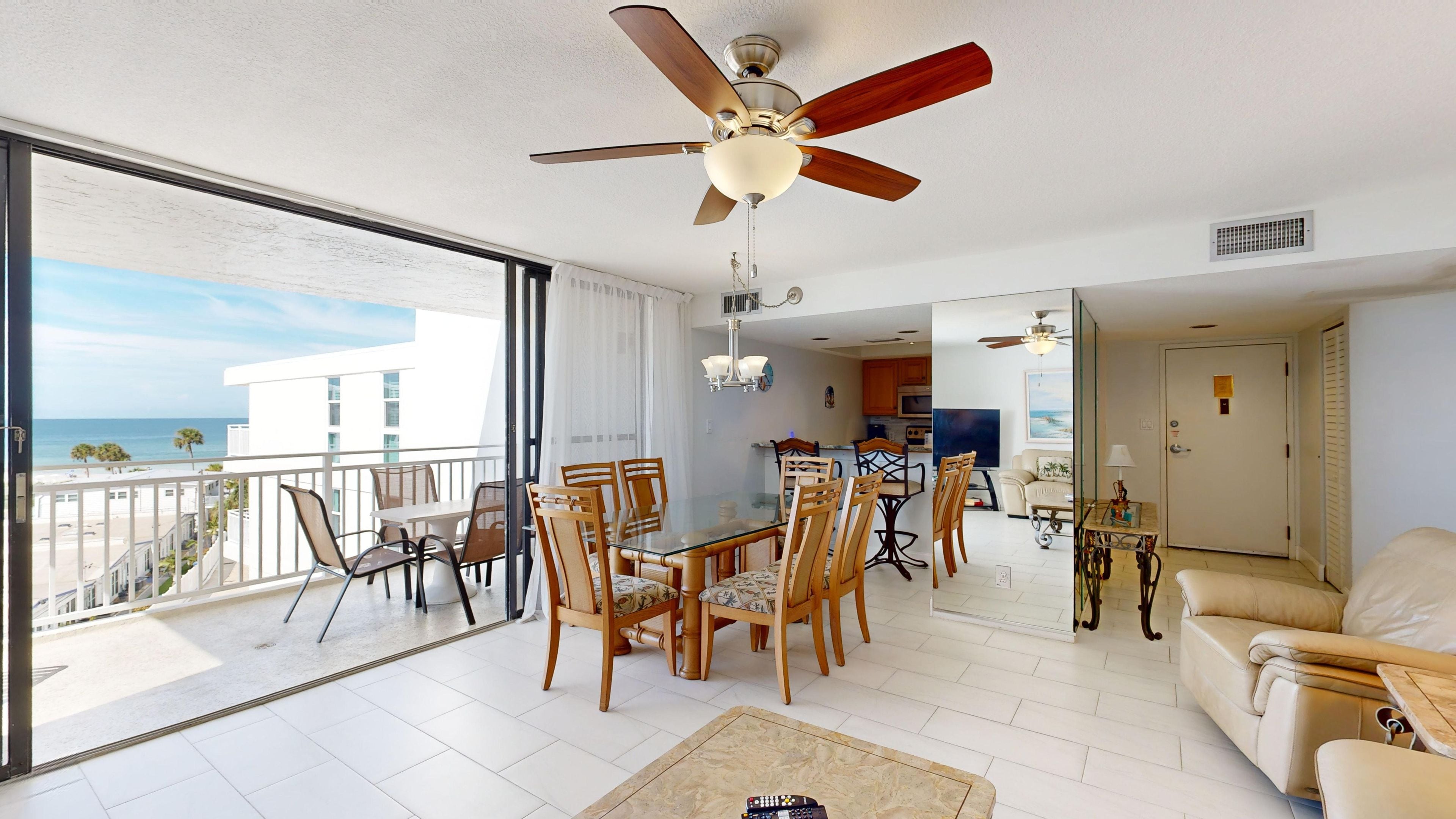 A spacious living area with a balcony, a dining table, and a sofa.