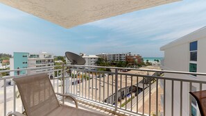 A balcony with a chair, a satellite dish, and a view of the beach and buildings. - House Of The Sun #503GS (Sarasota)