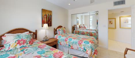 A hotel room with two beds, a large mirror, and artwork on the walls.