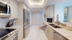 A modern kitchen with stainless steel appliances, a marble countertop, and a built-in oven. - House Of The Sun #503GS (Sarasota)