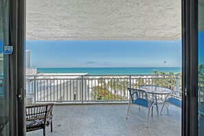 A balcony with a view of the beach, a table, chairs, and a bench. - House Of The Sun #414GF (Sarasota)